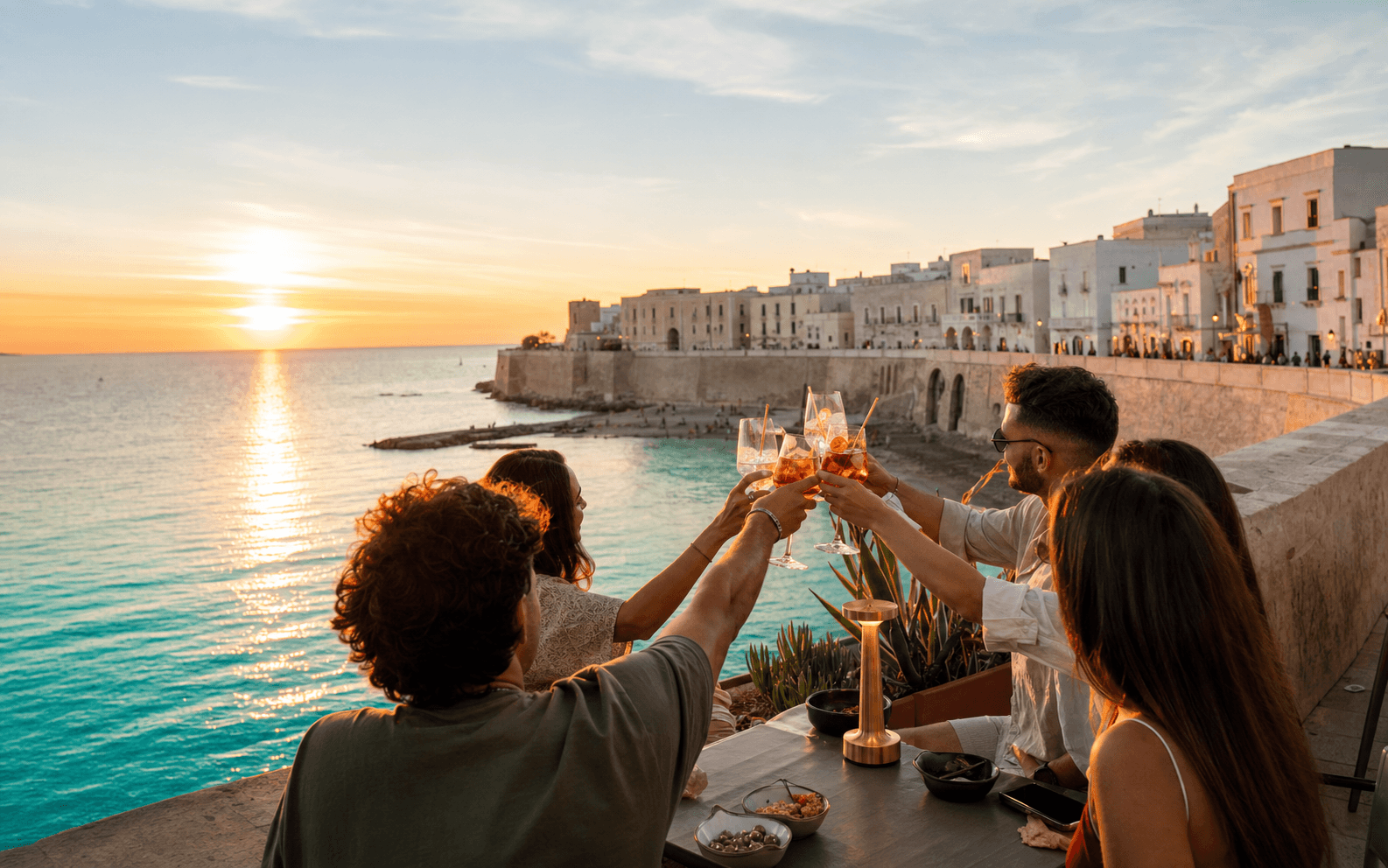 Amici brindano al tramonto sul mare di Gallipoli